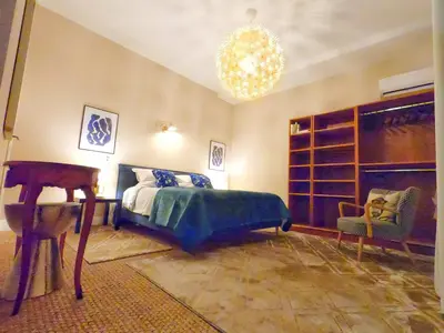 a bedroom with a bed and a chair and a chandelier at Maison ÉGLANTINE Historic 4 star with Air Conditioning in Carcassonne