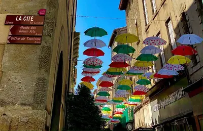 a bunch of umbrellas hanging between two buildings at Maison ÉGLANTINE Historic 4 star with Air Conditioning in Carcassonne