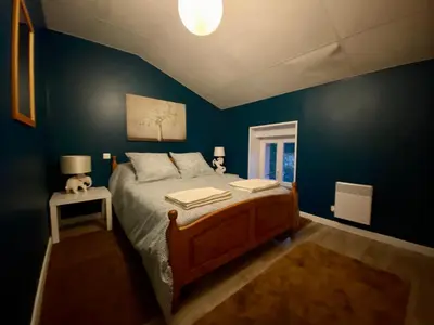 a bedroom with a large bed with blue walls at 3 Star 3 bed Air Conditioned QUERTINEUX 100m to Historic 4 Cathar Châteaux Lastours access to a very Pretty Riverside Garden!! in Lastours