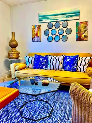 a living room with a yellow couch and blue pillows at 3 Star 3 bed Air Conditioned QUERTINEUX 100m to Historic 4 Cathar Châteaux Lastours access to a very Pretty Riverside Garden!! in Lastours