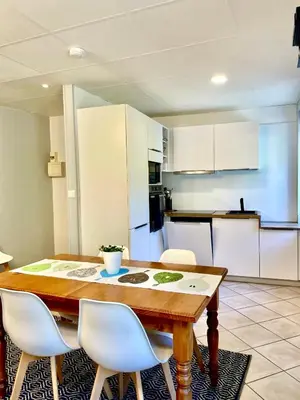 a kitchen with a wooden table and white cabinets at 3 Star 3 bed Air Conditioned QUERTINEUX 100m to Historic 4 Cathar Châteaux Lastours access to a very Pretty Riverside Garden!! in Lastours
