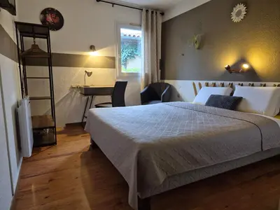 a bedroom with a bed and a desk and a table at Bel Hotel Restaurant la Gentilhommière in Trèbes