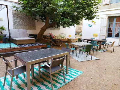 a group of tables and chairs under a tree at Le 9 de Cour, Chambre Caouette in Carcassonne
