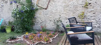 two chairs and a flower garden in front of a building at Le 9 de Cour, Chambre Caouette in Carcassonne