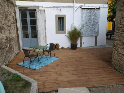 a patio with a table and chairs on a wooden deck at Le 9 de Cour, Chambre Caouette in Carcassonne