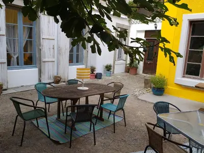 a table and chairs in a patio with a yellow building at Le 9 de Cour, Chambre Caouette in Carcassonne