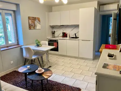 a kitchen with white cabinets and a table and chairs at Bijou SURDESPINE air conditioned 100m to Historic 4 Cathar Châteaux Lastours access to a very pretty riverside garden!! in Lastours
