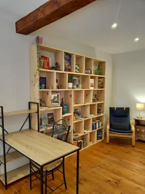 a room with a table and a chair and bookshelves at L'Oustal des amis in Belcaire