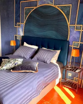 a bedroom with a large bed with a blue headboard at CheRiedel Bed & Breakfast & Art Gallery in Azillanet
