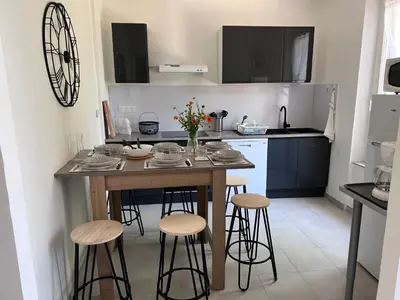 a kitchen with a table and stools in a room at Charmante maison Climatisée avec piscine au Calme à Carcassonne in Carcassonne