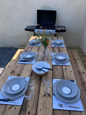 a wooden table with plates and glasses on it at Charmante maison Climatisée avec piscine au Calme à Carcassonne in Carcassonne