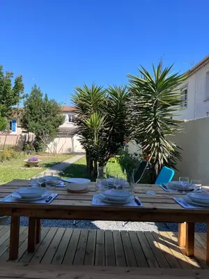 a wooden table with plates and glasses on it at Charmante maison Climatisée avec piscine au Calme à Carcassonne in Carcassonne