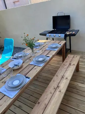 a wooden table with a grill and plates on it at Charmante maison Climatisée avec piscine au Calme à Carcassonne in Carcassonne