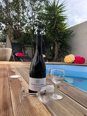 a bottle of wine on a wooden table with a glass at Charmante maison Climatisée avec piscine au Calme à Carcassonne in Carcassonne
