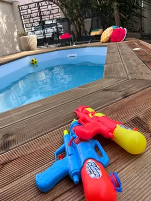 two toy guns sitting next to a swimming pool at Charmante maison Climatisée avec piscine au Calme à Carcassonne in Carcassonne