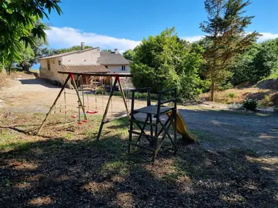 a swing set in a yard with a house at l'Oeil de Carcassonne in Caudebronde