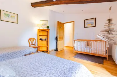a bedroom with two beds and a baby crib at l'Oeil de Carcassonne in Caudebronde