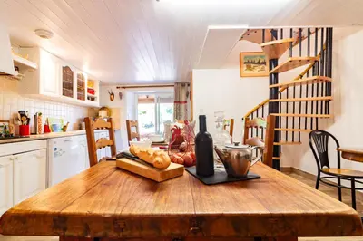 a wooden table in a kitchen with a bottle of wine at l'Oeil de Carcassonne in Caudebronde