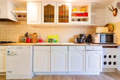 a white kitchen with white cabinets and appliances at l'Oeil de Carcassonne in Caudebronde