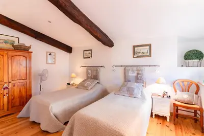 a bedroom with two beds and a chair at l'Oeil de Carcassonne in Caudebronde