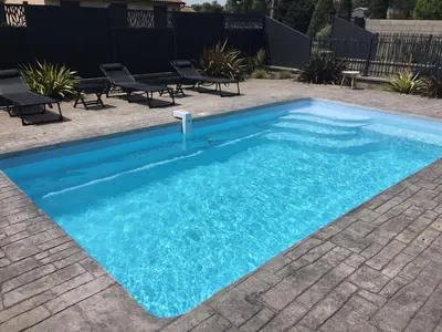 a swimming pool with blue water in a yard at Villa privative 3 chambres et piscine priv près Carcassonne in Carcassonne