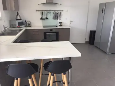 a kitchen with a white counter and stools in it at Villa privative 3 chambres et piscine priv près Carcassonne in Carcassonne