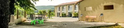 a building with green chairs next to a building at Domaine des Marronniers in Tourtrol