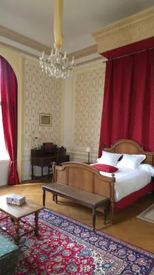 a bedroom with a bed with red curtains and a piano at Chateau de Pourpry in Damiatte