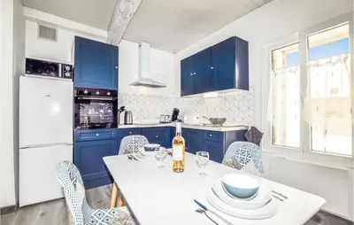 a kitchen with blue cabinets and a white table and chairs at 1 Bedroom Stunning Home In Bélesta in Bélesta