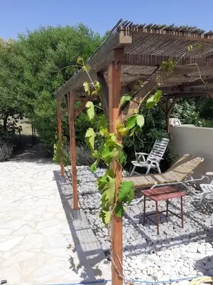 a wooden pergola with a bench and a chair at Le Chalet in Saint-Jean-de-Minervois