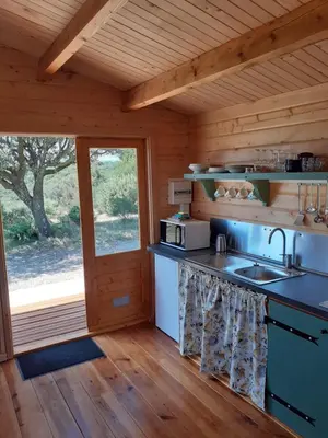 a kitchen in a log cabin with a sink and a window at Le Chalet in Saint-Jean-de-Minervois