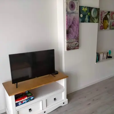 a flat screen tv sitting on top of a white entertainment center at Alaric Lodge: gîte champêtre avec parking privé. in Comigne
