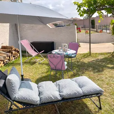 a group of chairs and a table with an umbrella at Alaric Lodge: gîte champêtre avec parking privé. in Comigne