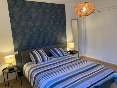 a bedroom with a bed with a blue headboard and two lamps at Appartement en centre ville avec roof top in Port-la-Nouvelle