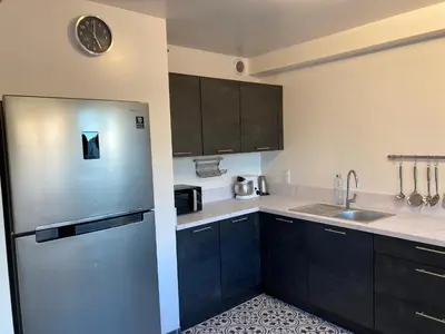 a kitchen with black cabinets and a stainless steel refrigerator at Appartement en centre ville avec roof top in Port-la-Nouvelle