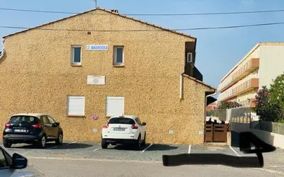 two cars parked in a parking lot in front of a building at La maison de Jade Le Mabrouka in Port-la-Nouvelle