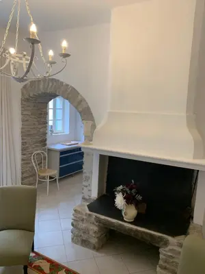 a living room with a stone fireplace with a chandelier at La Maison de Leontine in La Livinière