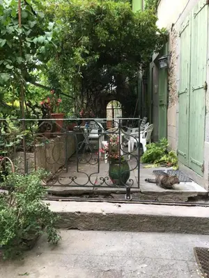 a iron gate with a table and chairs in a yard at La Maison de Leontine in La Livinière