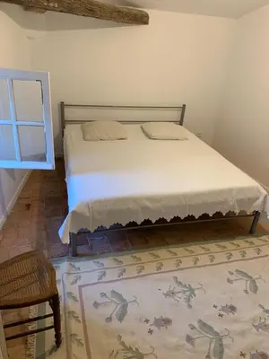 a bedroom with a bed and a chair and a rug at La Maison de Leontine in La Livinière