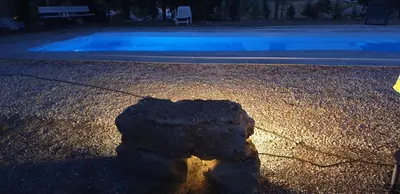 a rock sitting on the ground next to a swimming pool at La Pinède in Azillanet