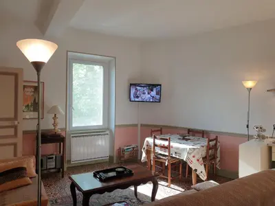 a living room with a table and a room with a couch at La Pinède in Azillanet