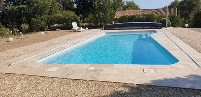 a swimming pool in a yard with a chair next to it at La Pinède in Azillanet