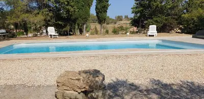 a swimming pool with two chairs and a rock at La Pinède in Azillanet
