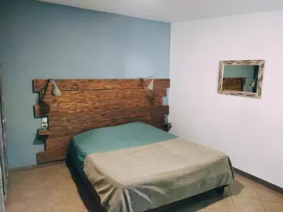 a bedroom with a bed with a wooden headboard at Aur Blan - 100m canal du midi au somail - Accueil vélo & Piscine in Le Somail