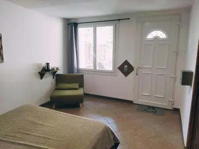 a bedroom with a bed and a chair and a door at Aur Blan - 100m canal du midi au somail - Accueil vélo & Piscine in Le Somail