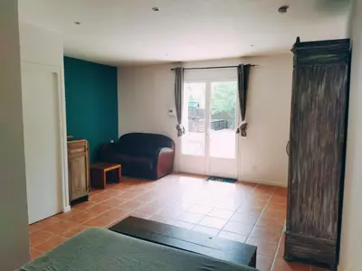 a living room with a couch and a sliding glass door at Aur Blan - 100m canal du midi au somail - Accueil vélo & Piscine in Le Somail