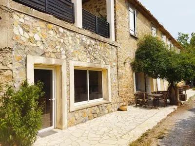 a stone building with windows and a table outside at Aur Blan - 100m canal du midi au somail - Accueil vélo & Piscine in Le Somail