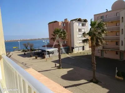 a balcony with palm trees in front of a building at Joli appartement avec grande et belle terrasse, au pied de la plage du Grazel! in Gruissan