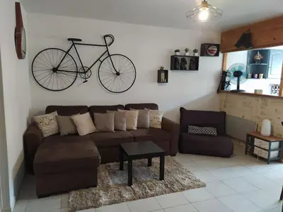 a living room with a couch and a bike hanging on the wall at Joli appartement avec grande et belle terrasse, au pied de la plage du Grazel! in Gruissan