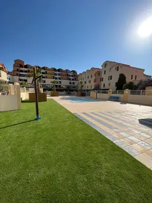 a courtyard with green grass and buildings in the background at Escale à Gruissan au coeur de la Marina in Gruissan